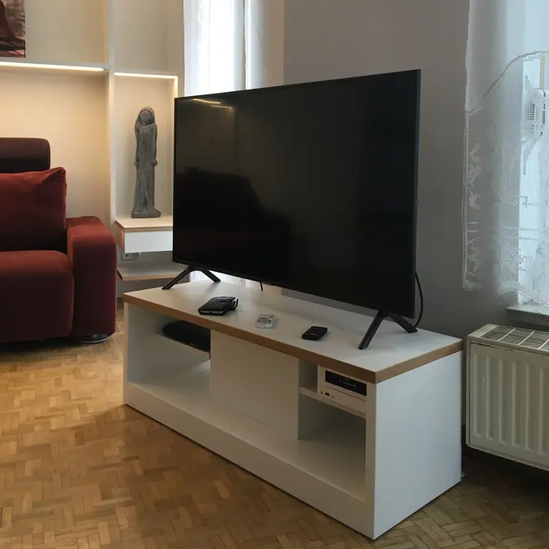 Weißes Lowboard mit Holzkante unter einem Fernseher in einem Wohnzimmer