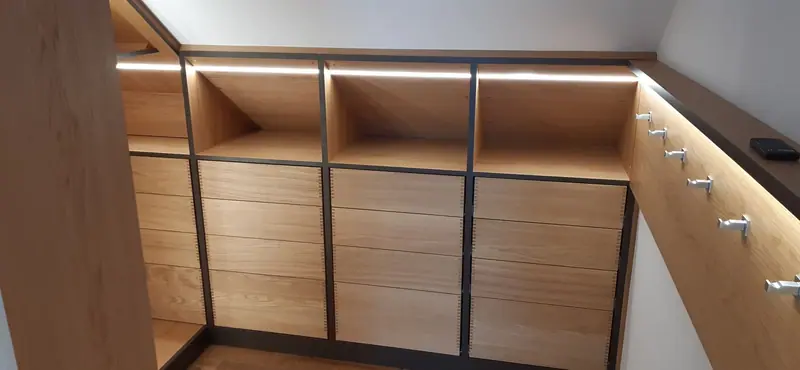 Reihe von Holzschubladen unter einer Dachschräge mit Lichtleiste